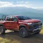 Red 2026 Chevy Colorado on a dirt road with a bike in the back.