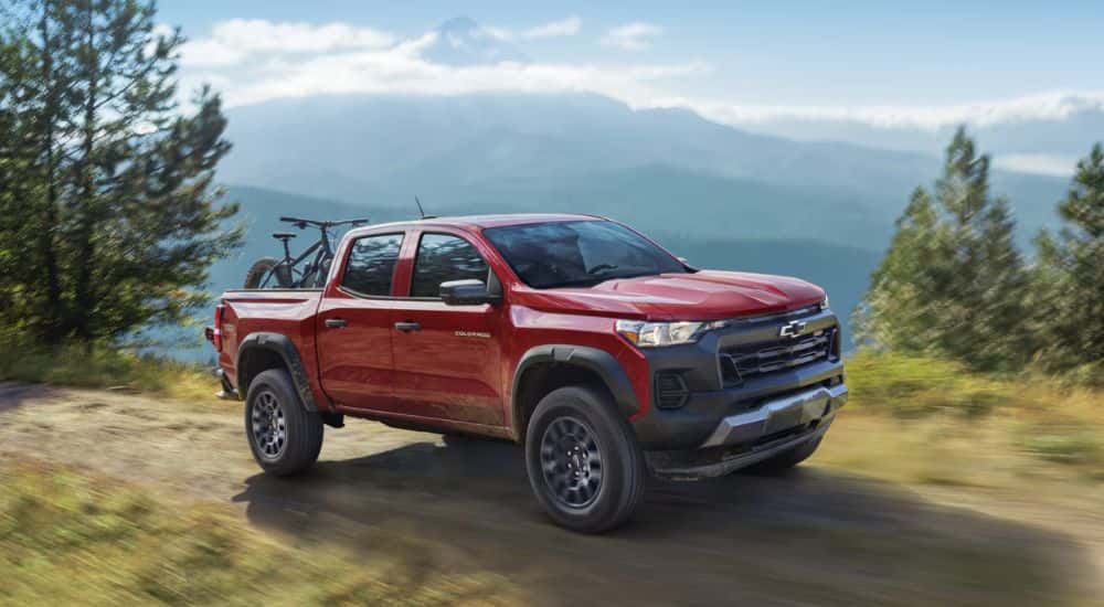 Red 2026 Chevy Colorado on a dirt road with a bike in the back.