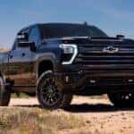 A black 2026 Chevy Silverado 2500 HD High Country Midnight Edition parked on a sandy beach.