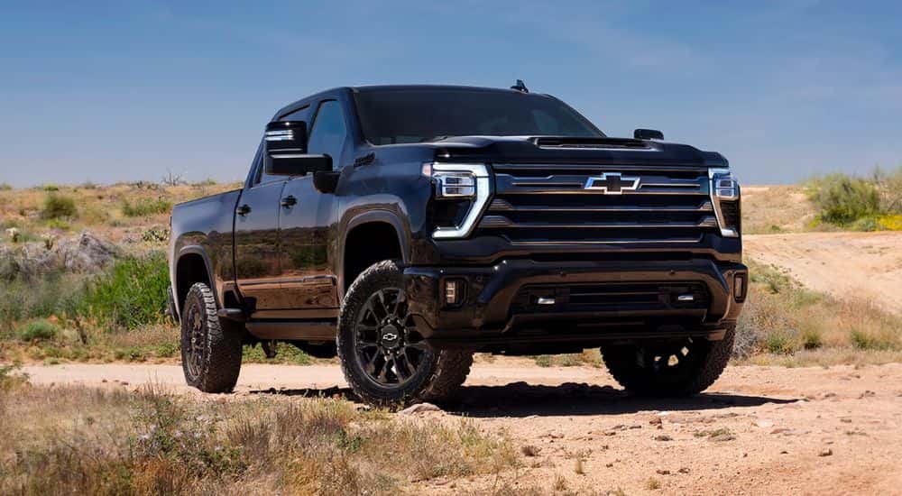 A black 2026 Chevy Silverado 2500 HD High Country Midnight Edition parked on a sandy beach.