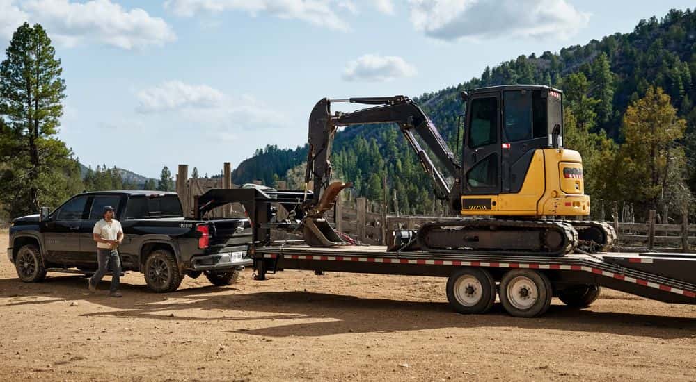 A black 2026 Chevy Silverado 2500 HD LTZ Trail Boss shown towing a mini excavator.
