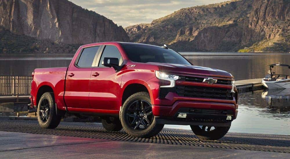A red 2026 Chevy Silverado LD Crew Cab RST parked by a docked boat.
