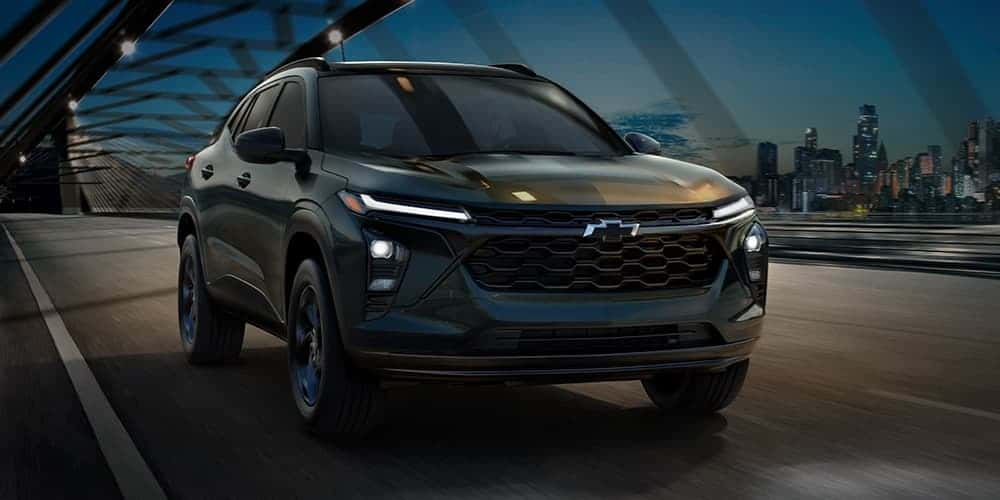 A black 2026 Chevy Trax driving on a bridge.