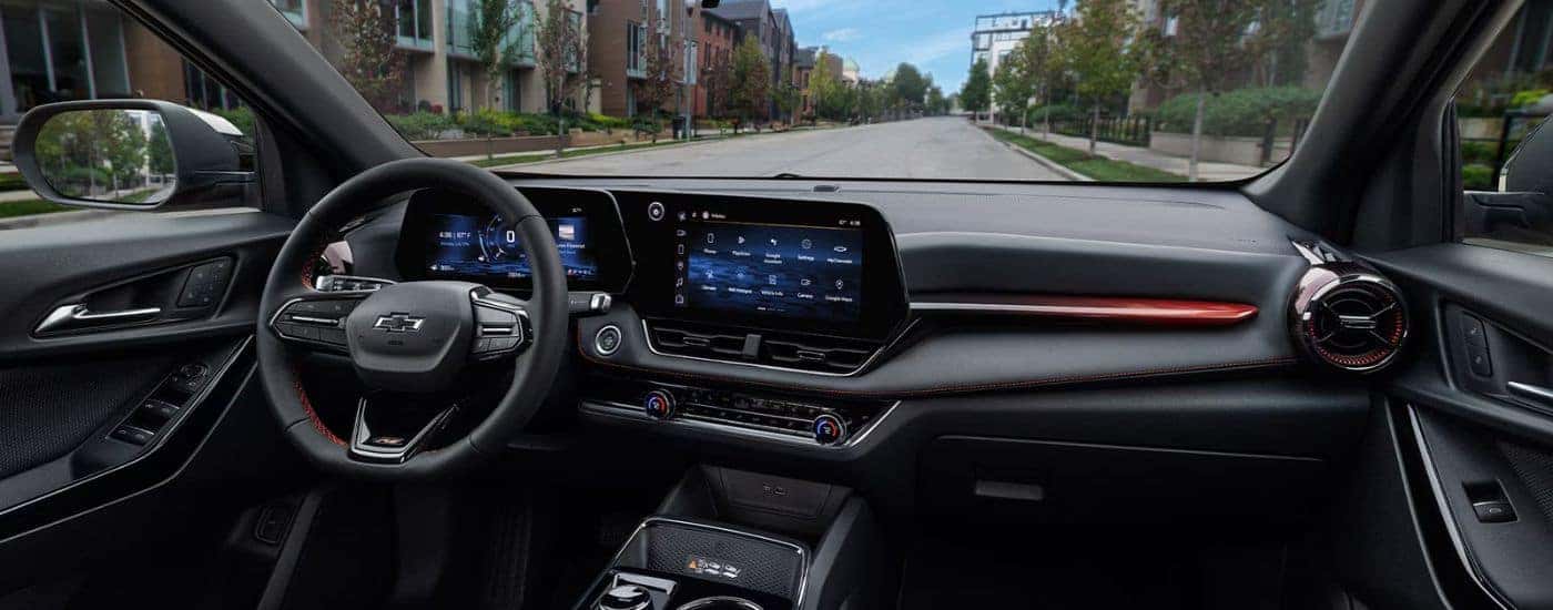 The black front interior of a 2026 Chevy Equinox showing the infotainment display and steering wheel.