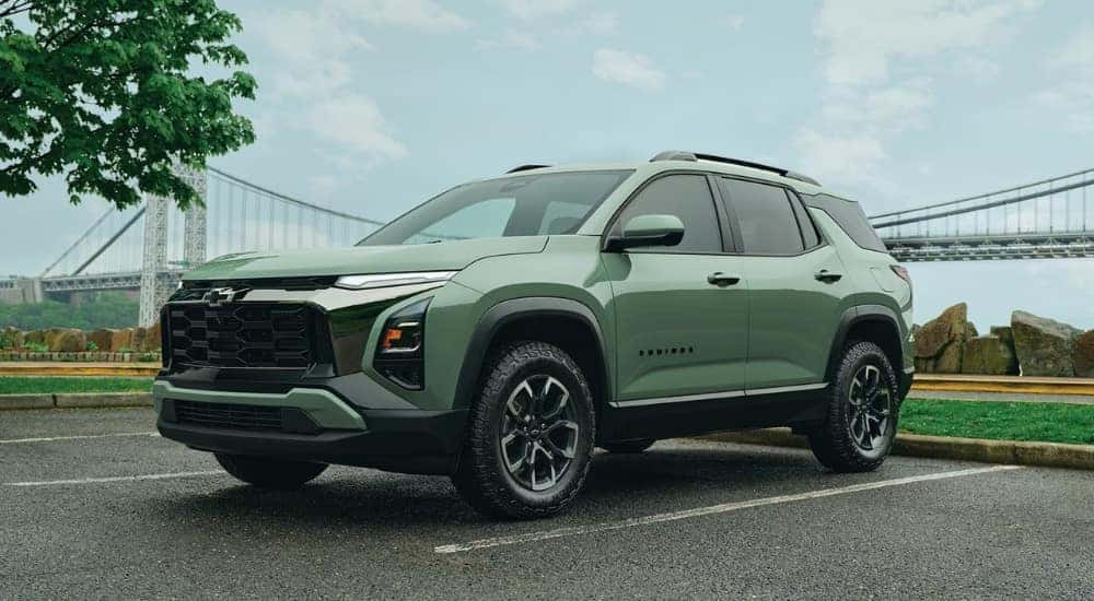 A green 2026 Chevy Equinox ACTIV driving away from a bridge.