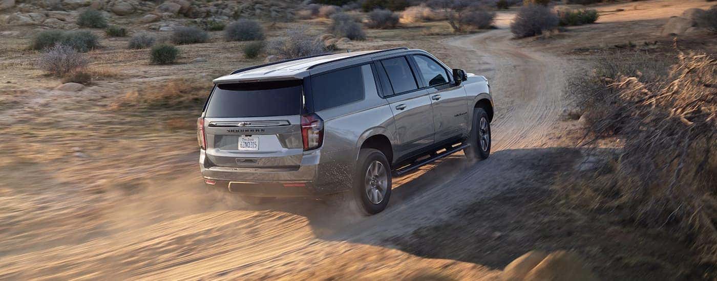 Rear view of a grey 2021 Chevy Suburban driving off-road.