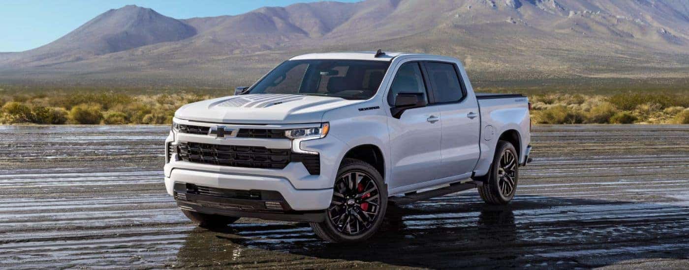 A White 2026 Chevrolet Silverado LD Stars and Steel Edition Truck Parked on a Wet Dirt Road.