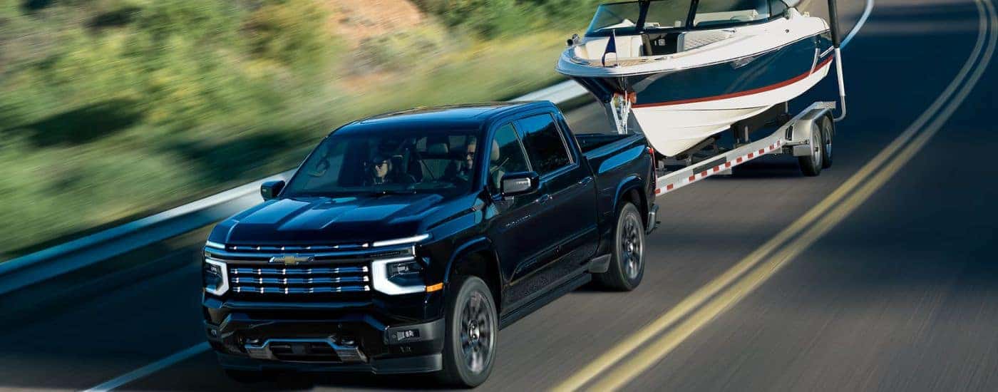 A black 2027 Silverado1500 High Country towing a boat.
