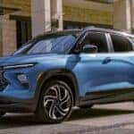 A blue 2027 Chevy Trailblazer RS parked next to a building.