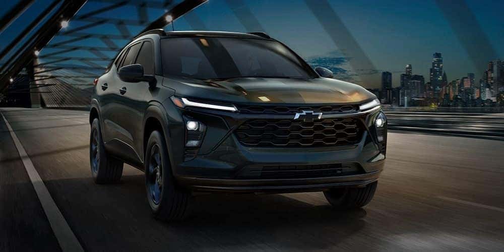 A black 2026 Chevy Trax driving on a bridge.