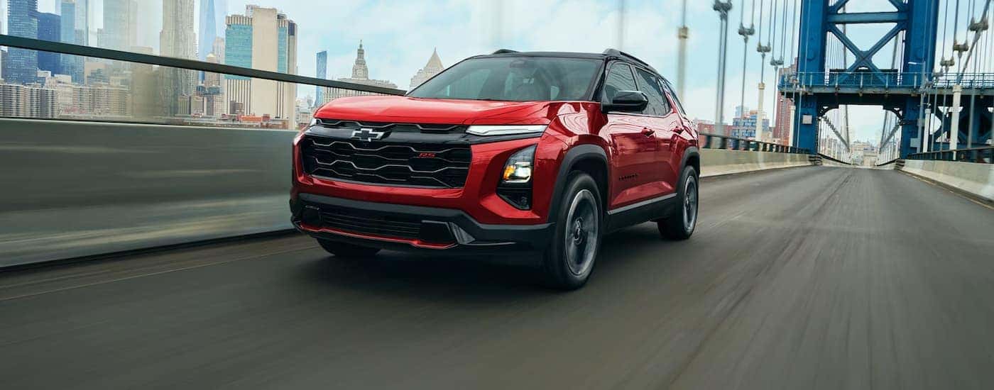 A red 2027 Chevy Equinox RS driving on a bridge
