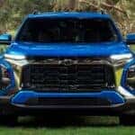 Front grille of a blue 2027 Chevy Equinox in a park.