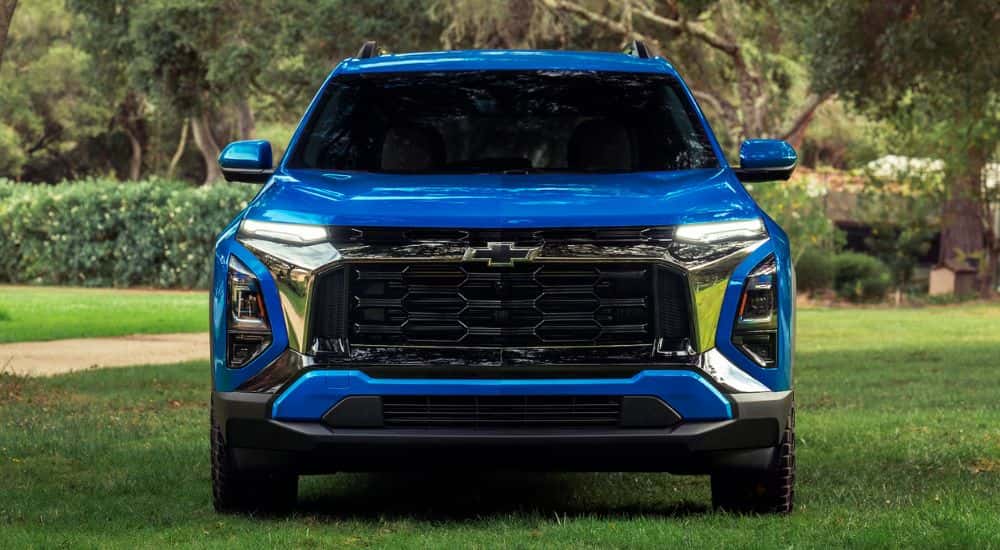 Front grille of a blue 2027 Chevy Equinox in a park.