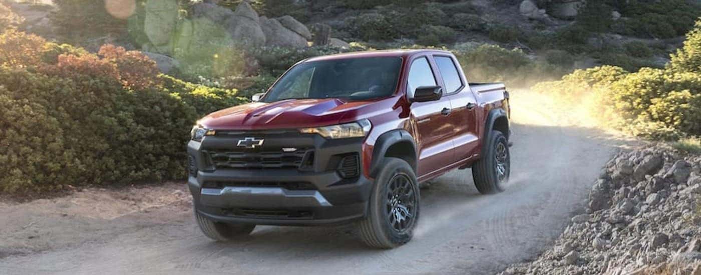 A red 2023 Chevy Colorado driving on a dirt road.