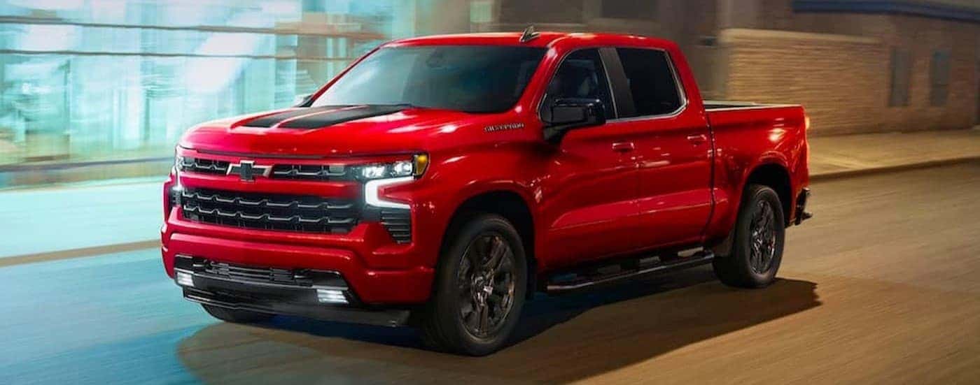 A red 2023 Chevy Silverado 1500 RST driving in a city.