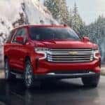 A red 2024 Chevy Suburban driving on a snowy day.
