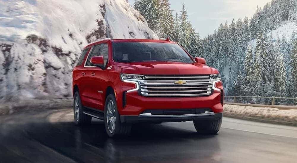 A red 2024 Chevy Suburban driving on a snowy day.