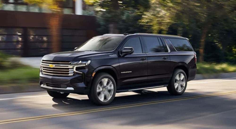 A blue 2024 Chevy Suburban High Country driving in a city.