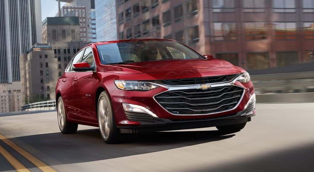 Red 2024 Chevy Malibu driving out of a city.