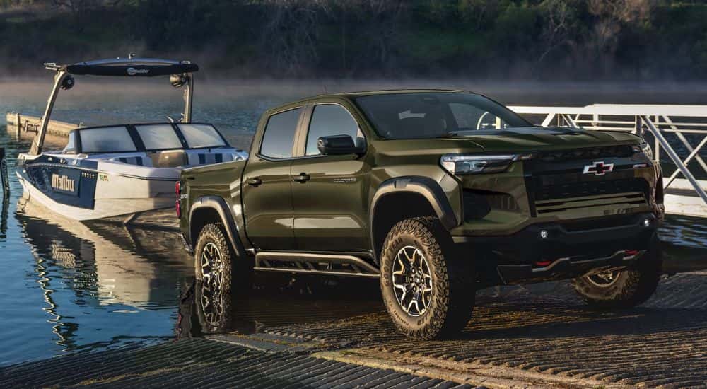 Green 2027 Chevy Colorado Z71 towing a boat into water.