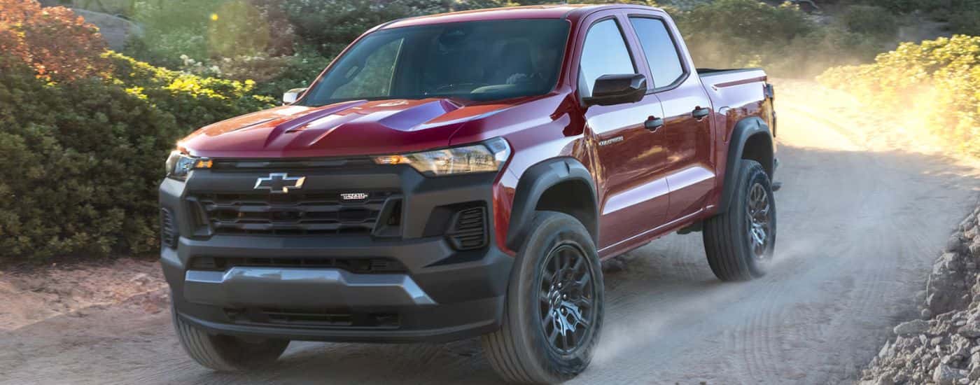 Red 2027 Chevy Colorado Trail Boss driving on a dirt road.