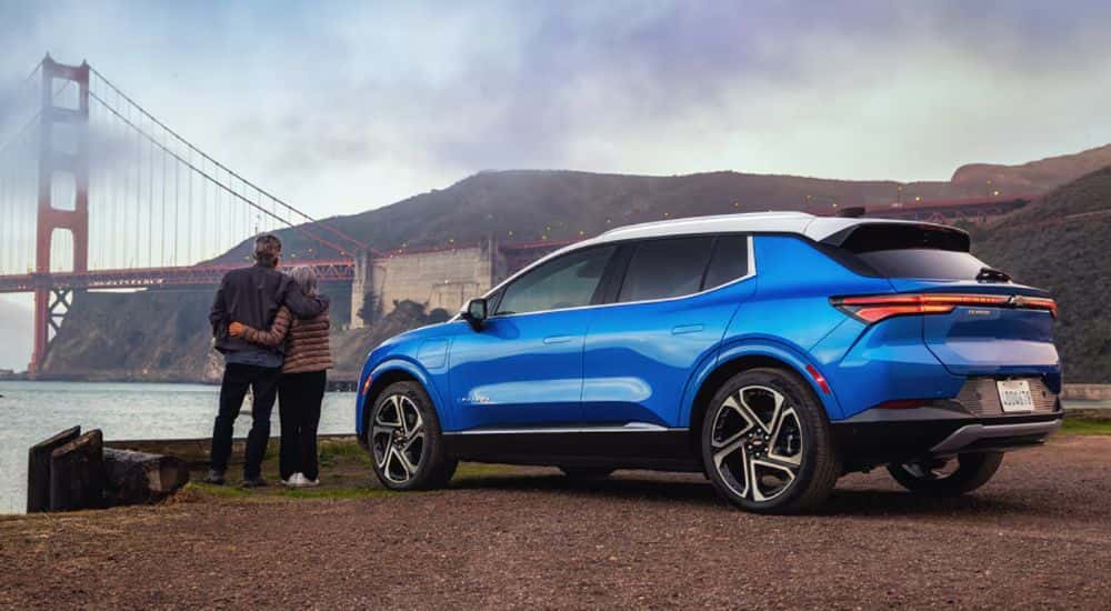 A couple standing by a blue 2027 Chevy Equinox EV LT 2.