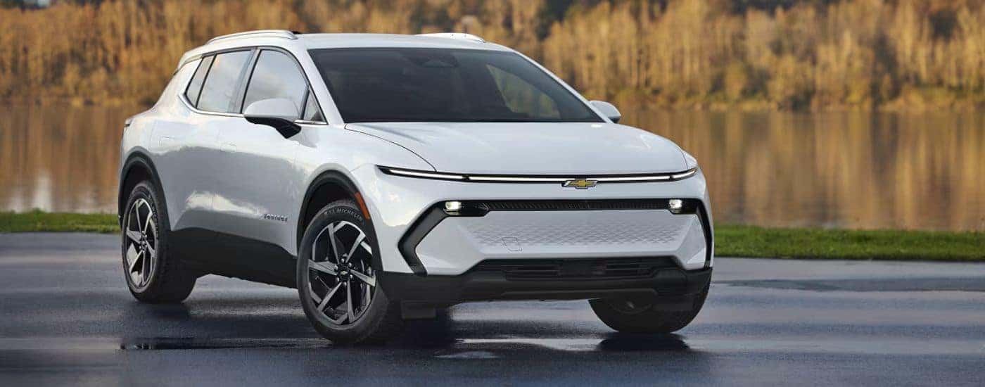 A white 2027 Chevy Equinox EV parked by a lake.