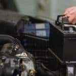 Male mechanic changing car battery