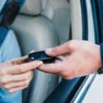 close up of man handing car keys to woman in car