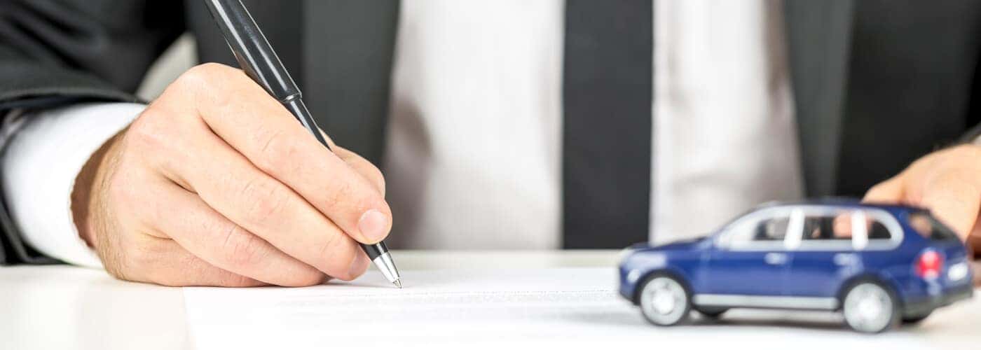 Car purchase paperwork with tiny blue car