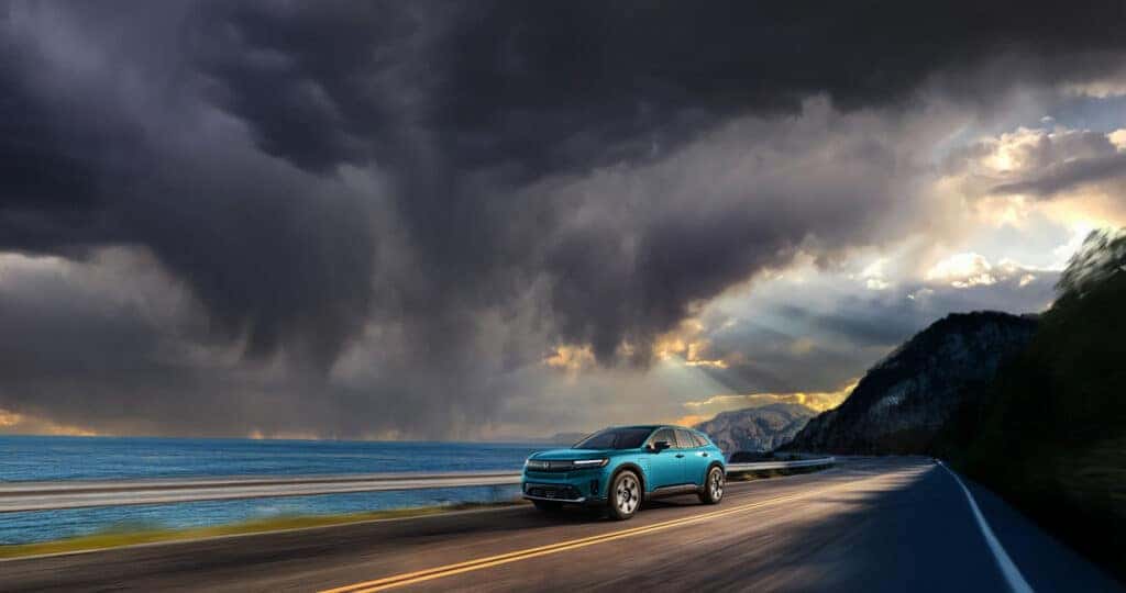 2024-Honda-Prologue-driving-next-to-the-ocean-with-a-stormy-sky-above