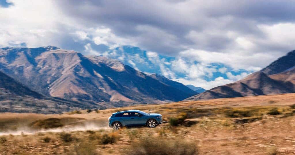 2024-Honda-Prologue-driving-opn-a-dirt-road-with-mountain-ranges-in-the-distance