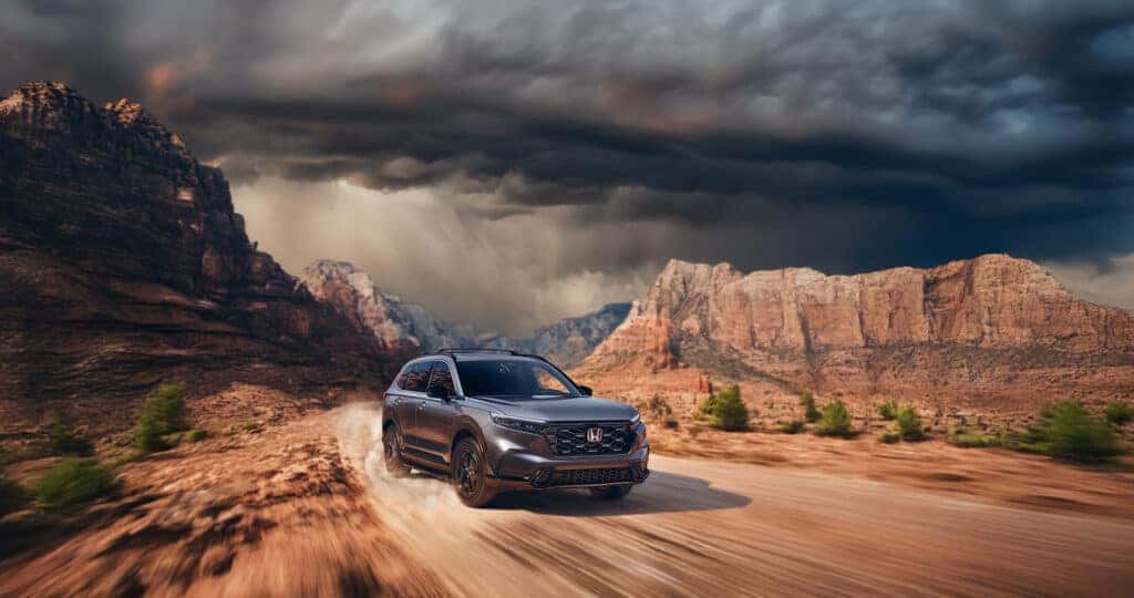 2025 Honda CR-V driving through a desert canyon with storm clouds in the sky