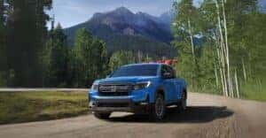 2025-Honda-ridgeline-Diffused-Blue-driving-on-gravel-road-with-motorbikes-in-the-truck-bed