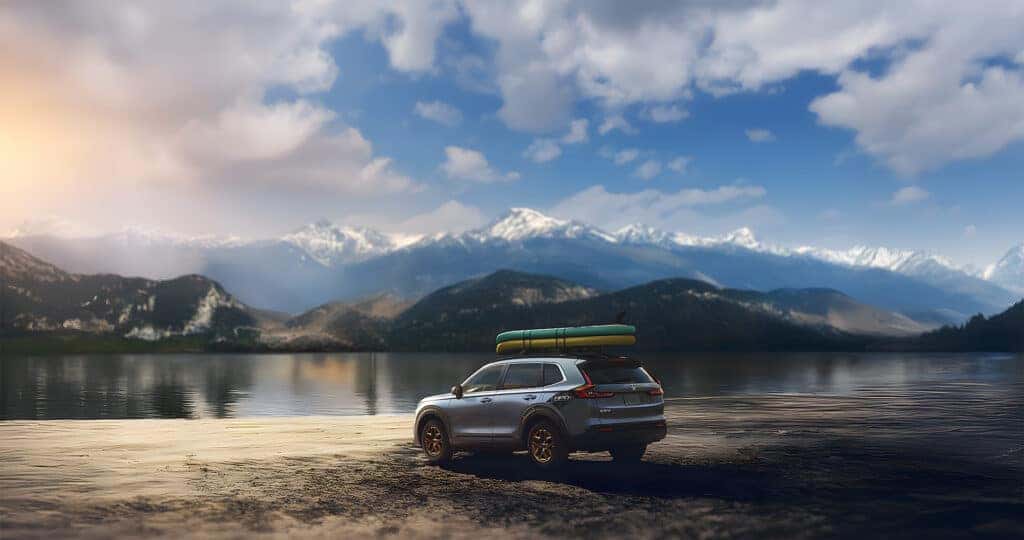 2025 Honda CR-V HPD edition with paddleboards on the roof parked on the beach of a mountain lake