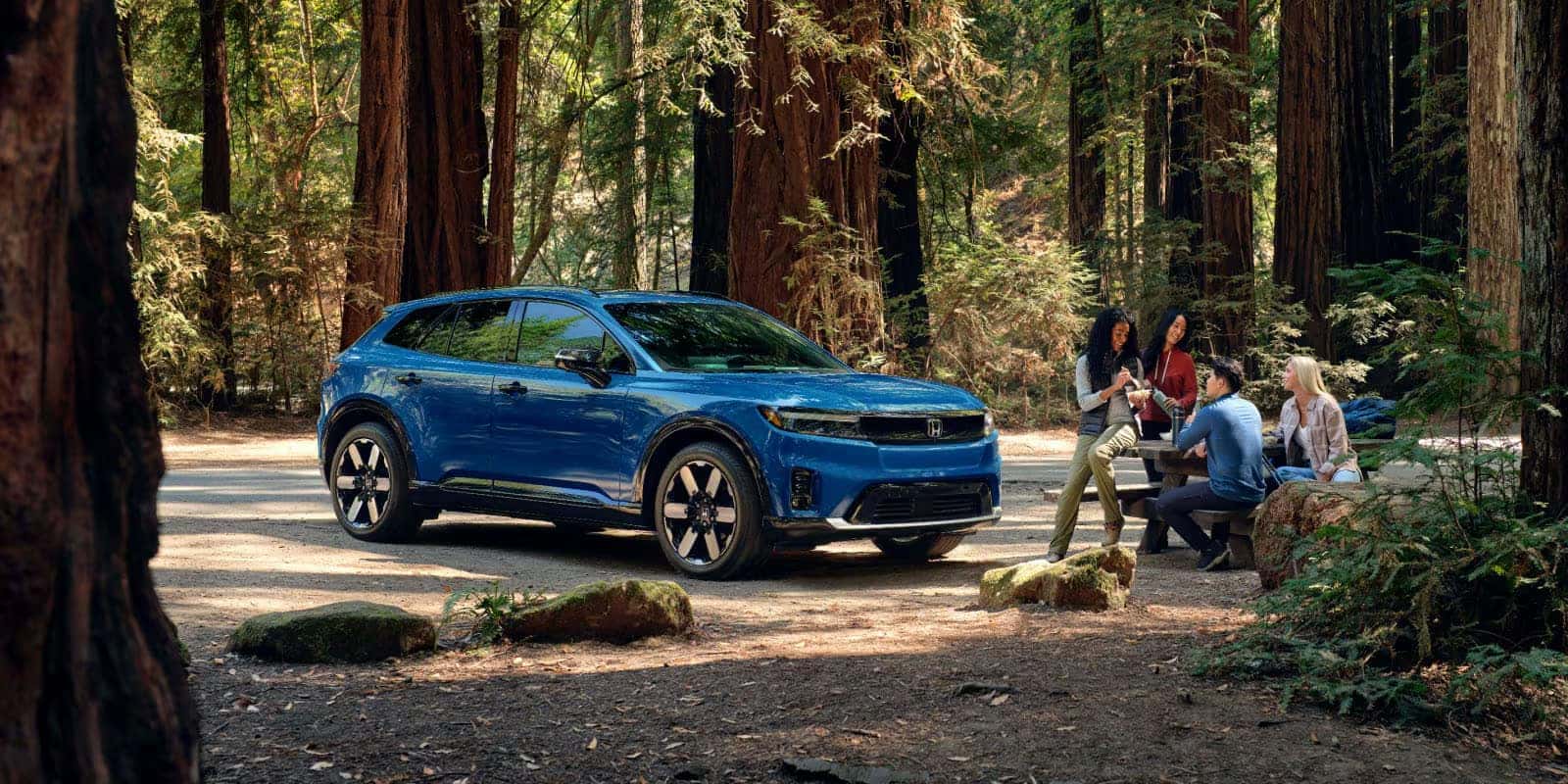 2026 Honda Prologue parked at a wooded campsite with friends nearby