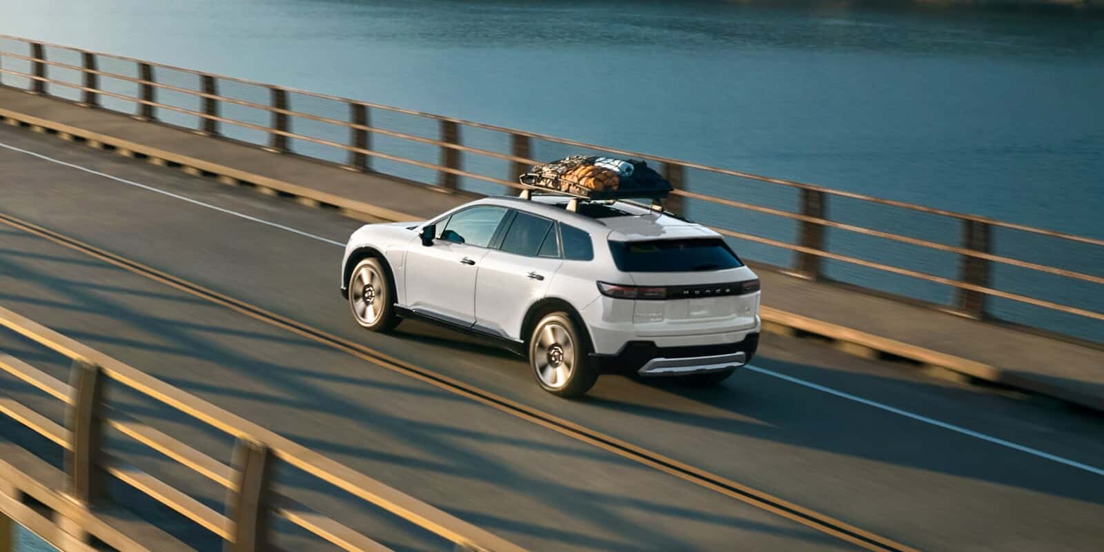 2026 Honda Prologue driving across a bridge with cargo loaded on the roof rack