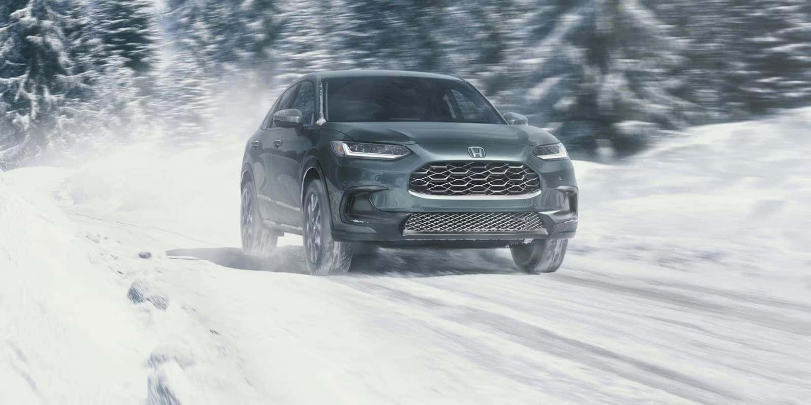 2026 Honda HR-V driving on a snow-covered mountain road, showcasing all-wheel-drive confidence and stable handling in winter conditions