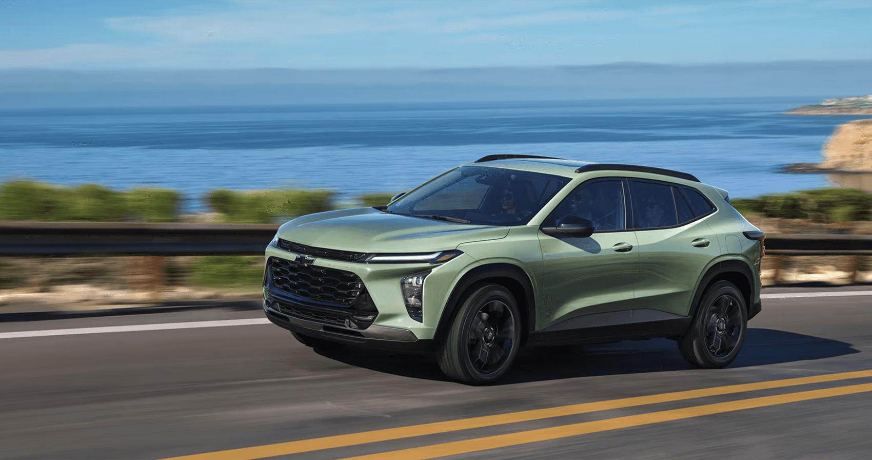 2026 Chevrolet Trax driving along a coastal highway, showcasing compact size, modern styling, and everyday efficiency