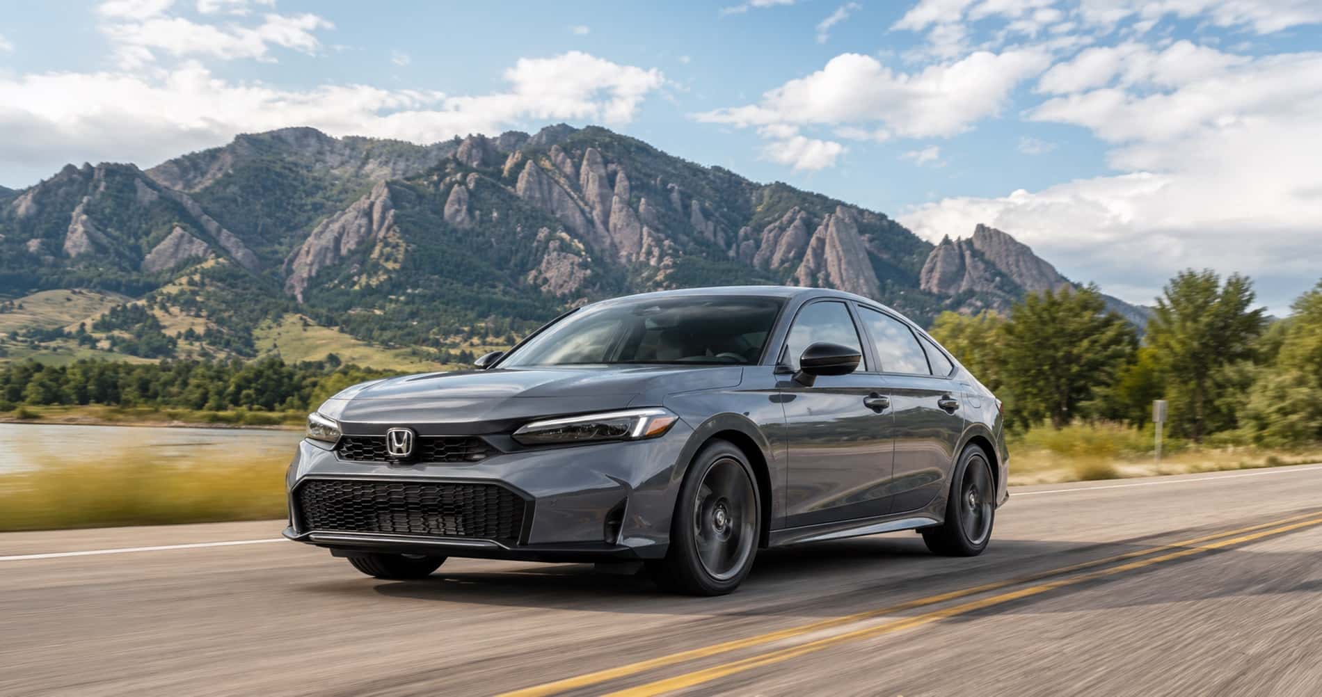 2026 Honda Civic driving on a scenic Boulder road with the Flatirons in the background, shown from a dynamic front three-quarter angle.