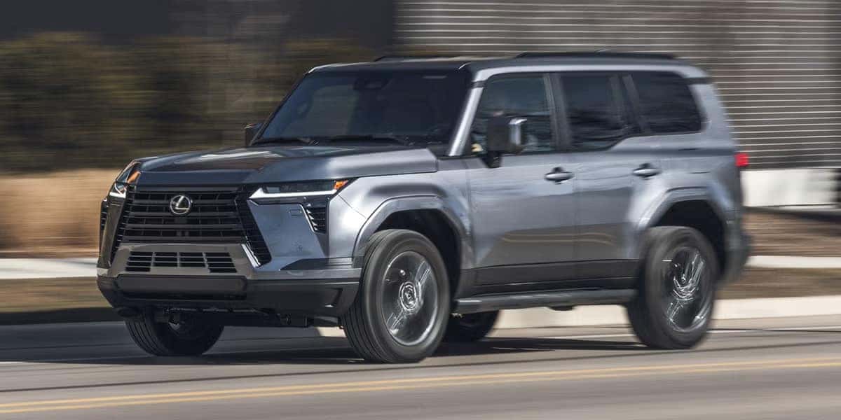 Silver Lexus GX driving on a paved road with motion blur in the background.