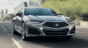 2023 gray acura tlx whizzing down a city street