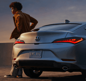 man stands against a 2023 acura integra in a parking lot at dusk