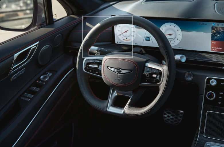 Driver's view of a Genesis GV80 Coupe showing the steering wheel and digital instrument display, at Genesis of North Cincinnati.