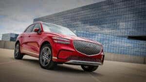 Detailed view of the 2026 Genesis Electrified GV70’s design elements, including the gradient G-Matrix Crest Grille with diamond pattern, Two-Line MLA Headlamps, 20-inch diamond-cut alloy wheels, and sleek rear spoiler with chrome bumper accents.