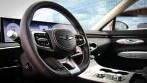 Interior view of the 2026 Genesis Electrified GV70 showcasing ambient lighting, digital displays, and premium technology features including a wide infotainment screen and wireless smartphone integration.