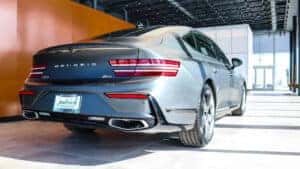 Rear view of the 2026 Genesis G80 luxury sedan, highlighting sleek curves, slender two-line LED tail lamps, and aerodynamic design.