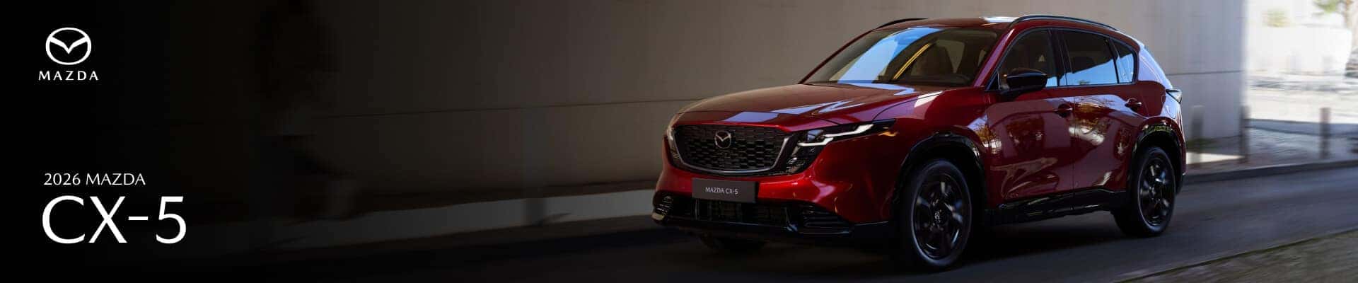 A red 2026 Mazda CX-5 drives down an alley.