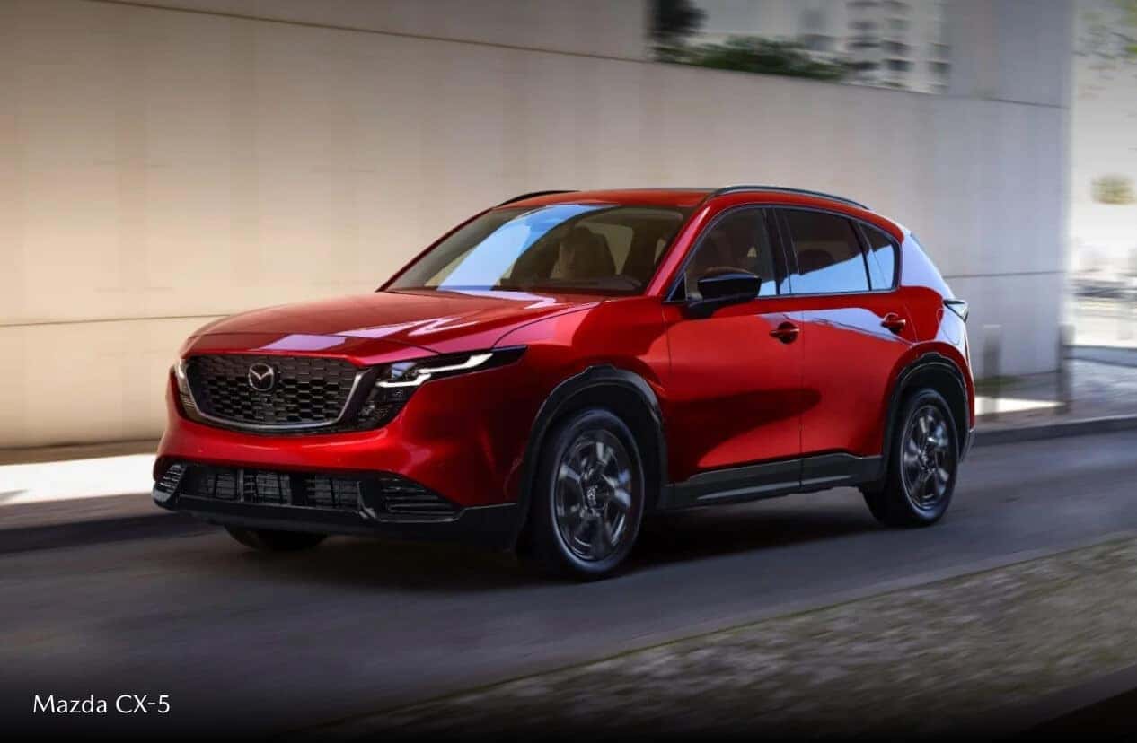 Exterior action shot of a red Mazda CX-5 driving down a city street.