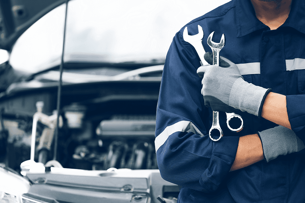 man holding tools with vehicle hood popped in background